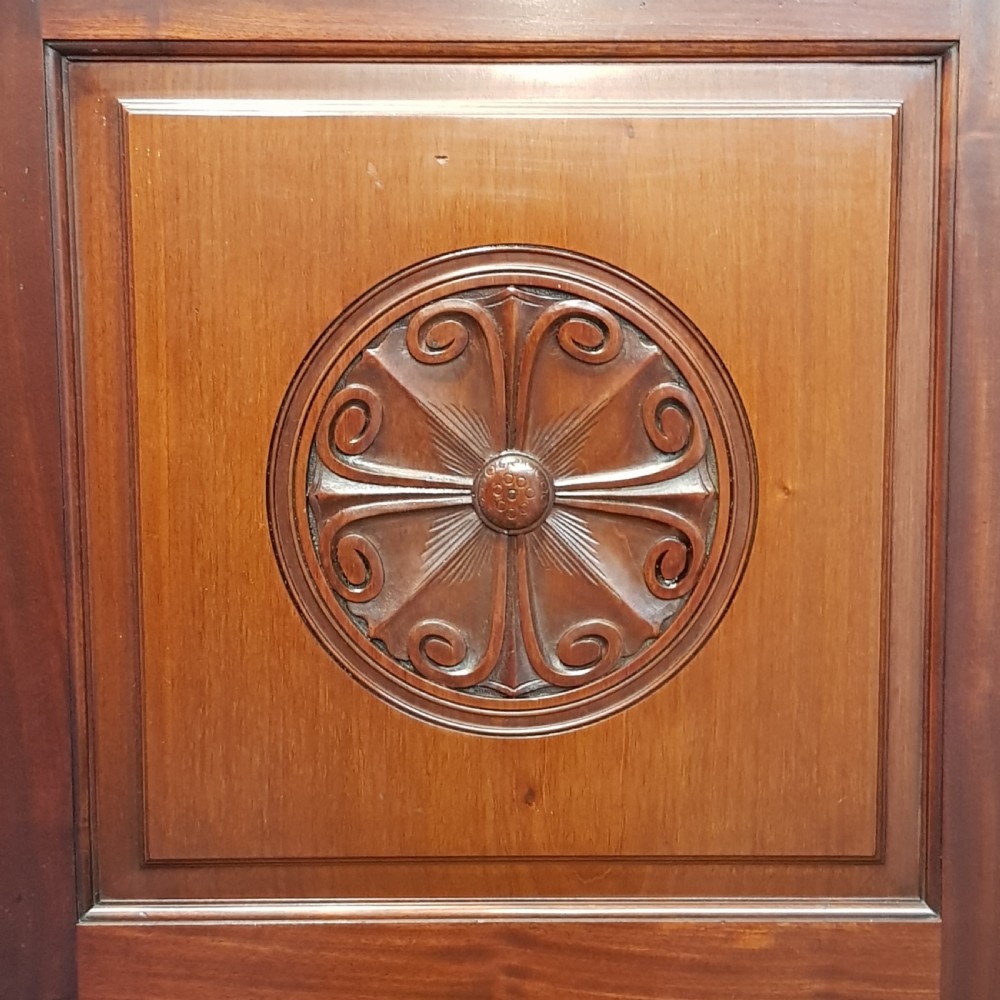 A late Victorian dark mahogany triple wardrobe featuring a central full-length mirror flanked by two timber panel doors with carved circular rosettes. View V