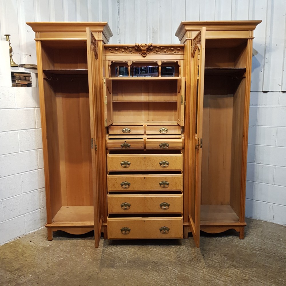 An antique Victorian satin walnut and maple combination wardrobe featuring two tall outer sections with mirrored doors flanking a central chest of drawers and small upper cupboard. View II