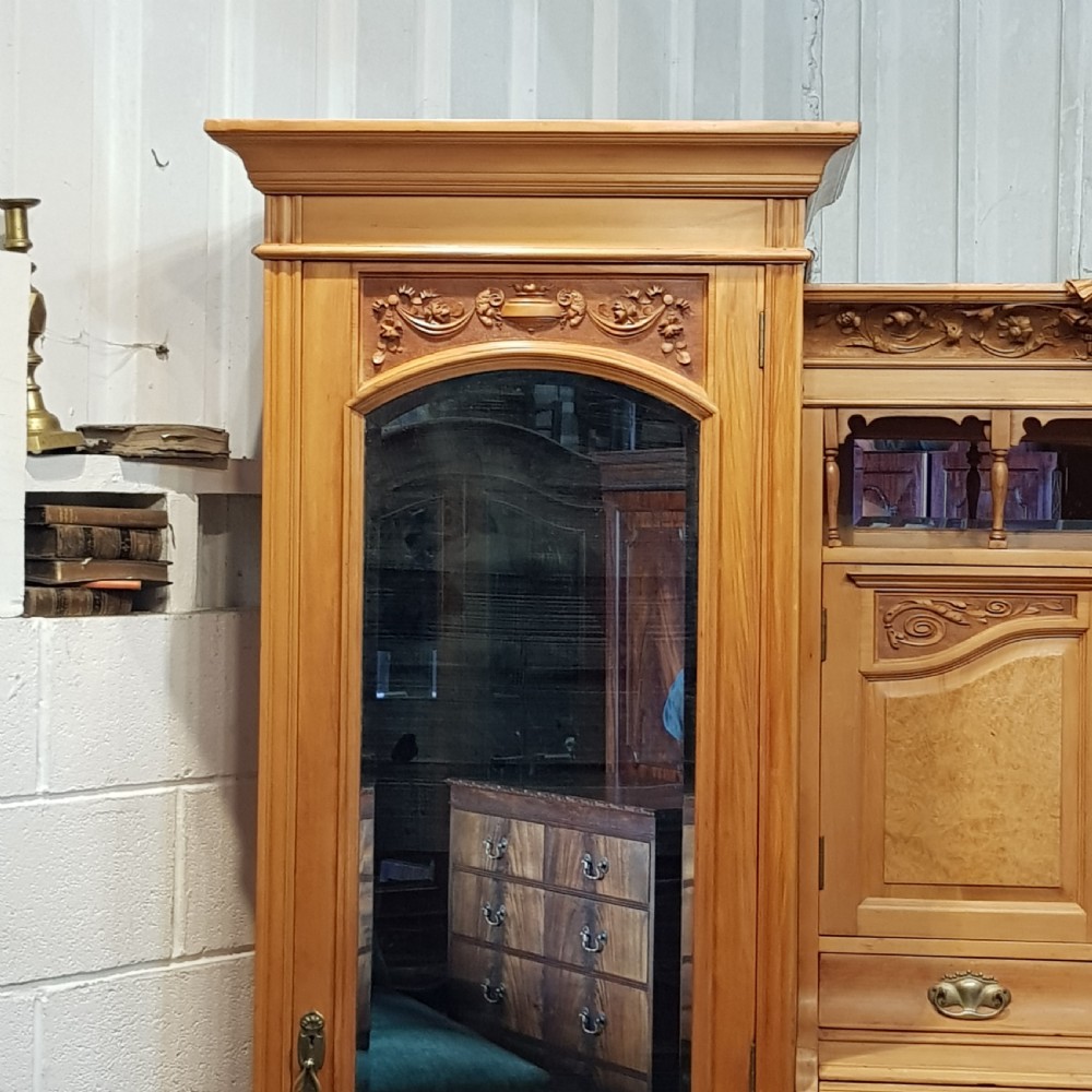 An antique Victorian satin walnut and maple combination wardrobe featuring two tall outer sections with mirrored doors flanking a central chest of drawers and small upper cupboard. View V