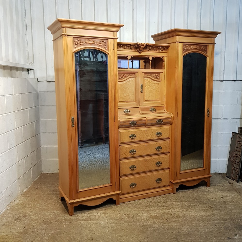 An antique Victorian satin walnut and maple combination wardrobe featuring two tall outer sections with mirrored doors flanking a central chest of drawers and small upper cupboard. View IX