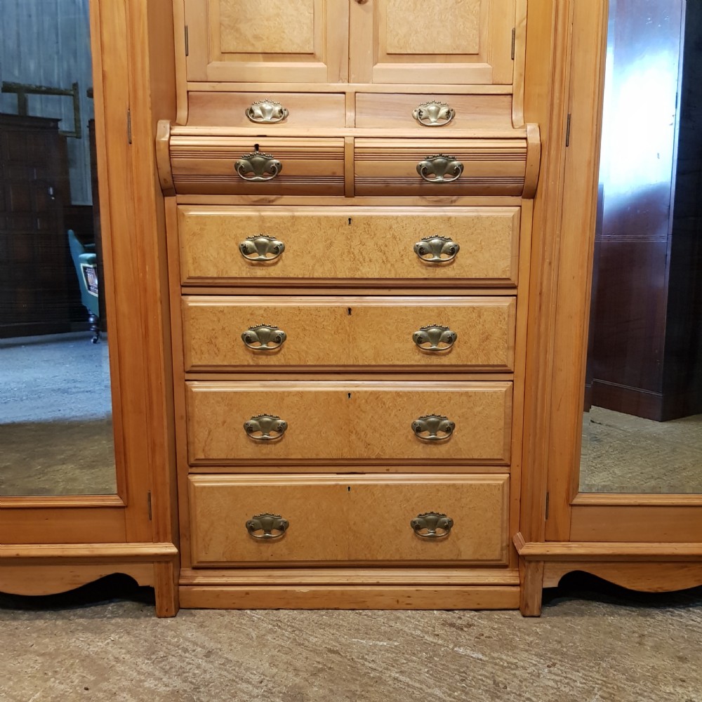 An antique Victorian satin walnut and maple combination wardrobe featuring two tall outer sections with mirrored doors flanking a central chest of drawers and small upper cupboard. View XII