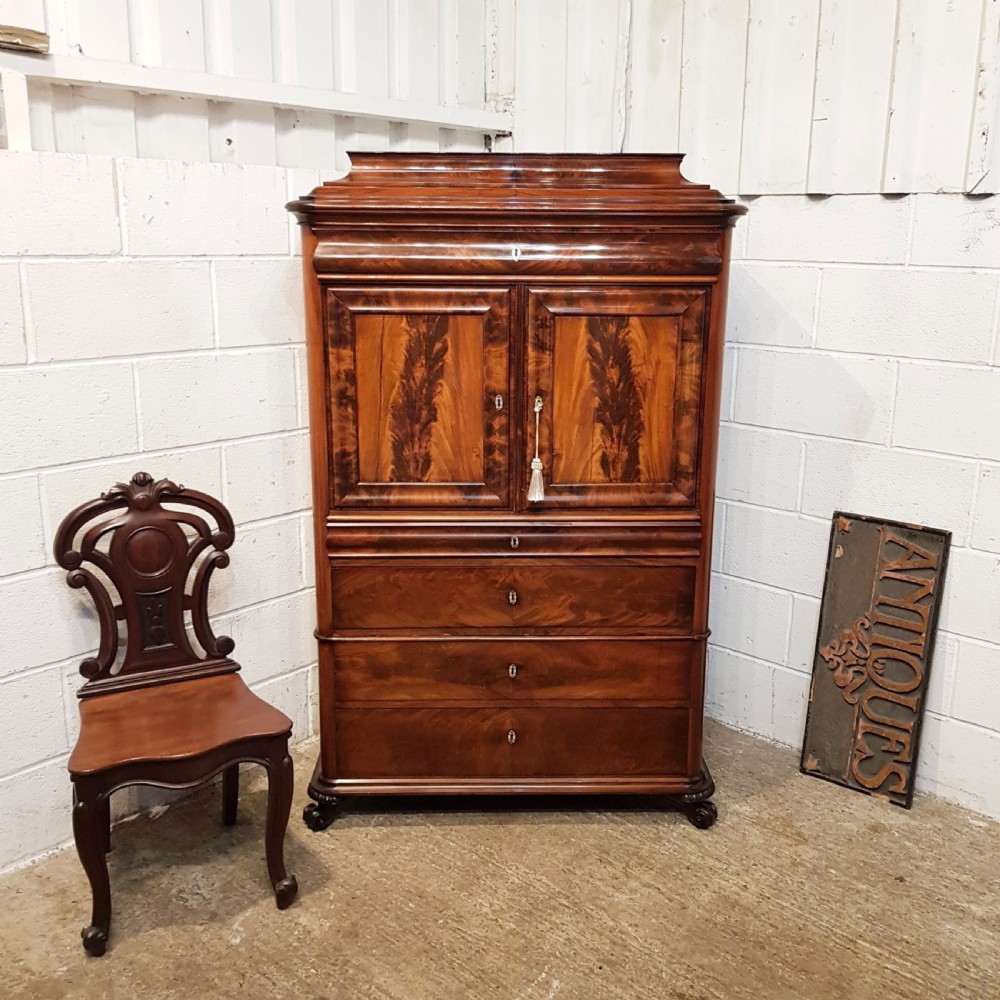 A nineteenth-century Biedermeier flame mahogany tall storage cabinet featuring double upper doors with figure-matched veneer and three full-width lower drawers.