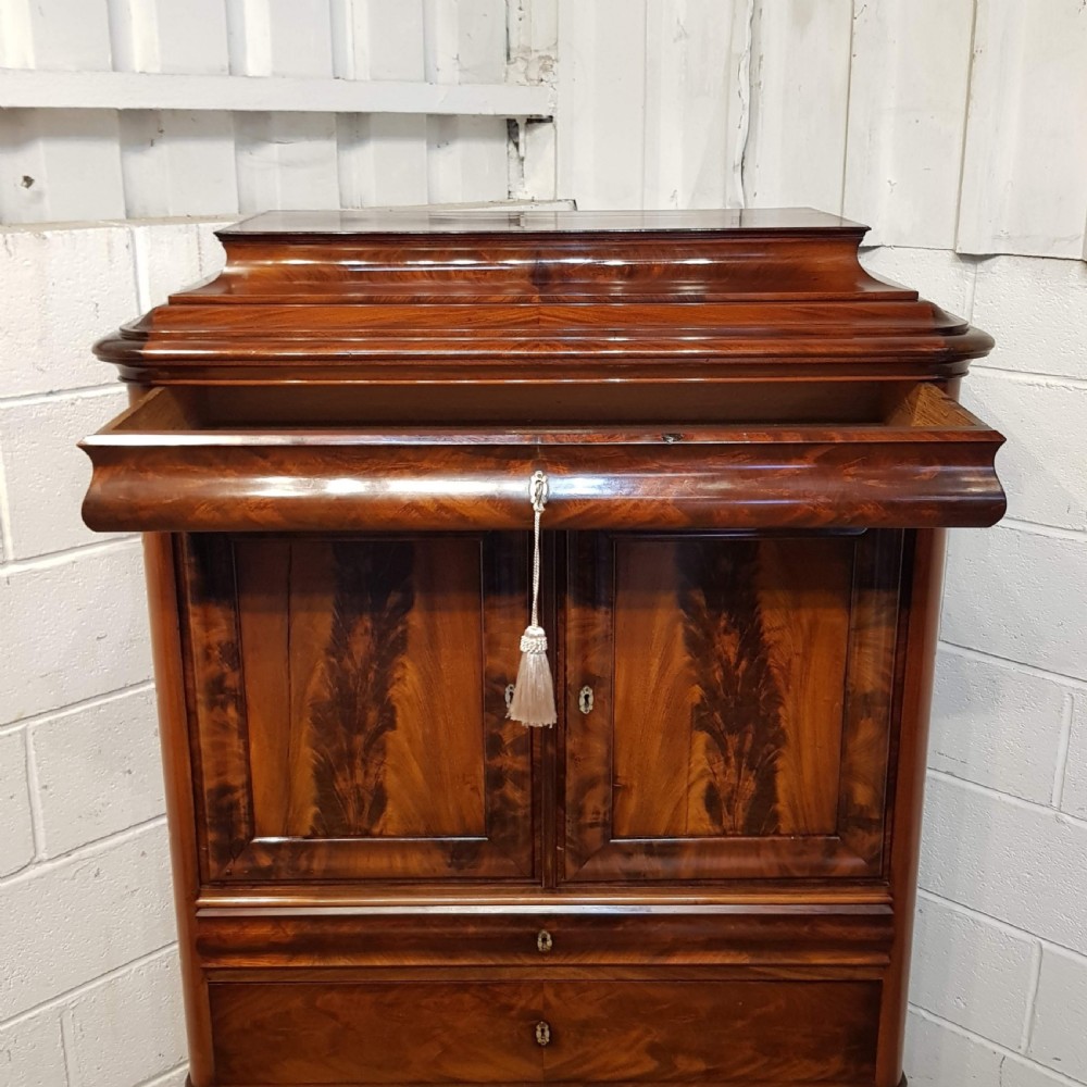 A nineteenth-century Biedermeier flame mahogany tall storage cabinet featuring double upper doors with figure-matched veneer and three full-width lower drawers. View VII
