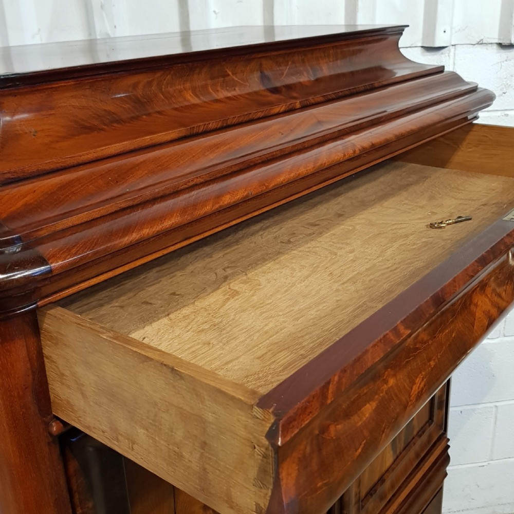 A nineteenth-century Biedermeier flame mahogany tall storage cabinet featuring double upper doors with figure-matched veneer and three full-width lower drawers. View VIII