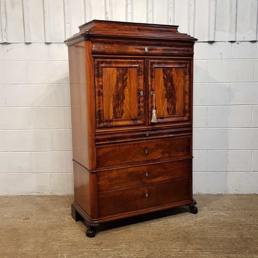 A nineteenth-century Biedermeier flame mahogany tall storage cabinet featuring double upper doors with figure-matched veneer and three full-width lower drawers. View IX