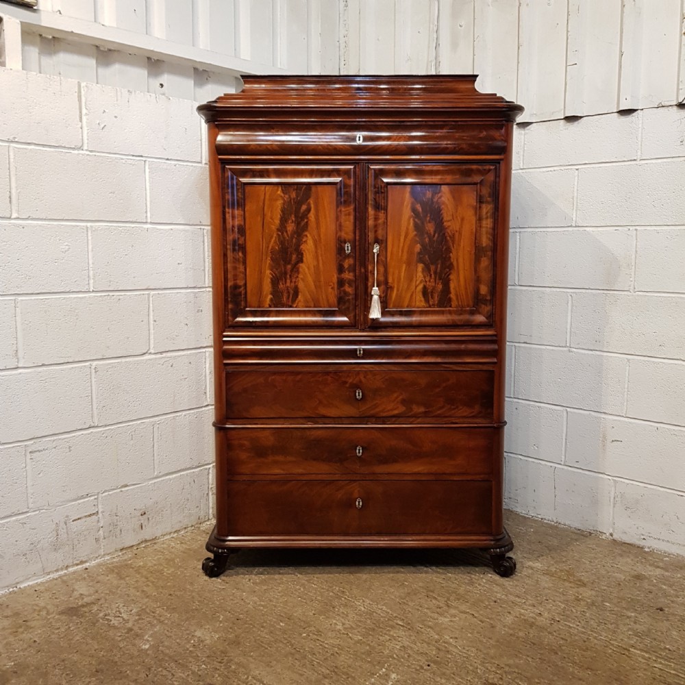 A nineteenth-century Biedermeier flame mahogany tall storage cabinet featuring double upper doors with figure-matched veneer and three full-width lower drawers. View X