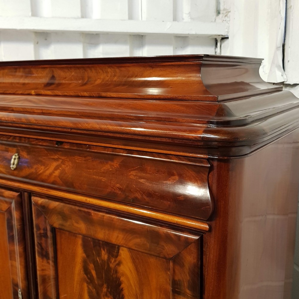 A nineteenth-century Biedermeier flame mahogany tall storage cabinet featuring double upper doors with figure-matched veneer and three full-width lower drawers. View XI