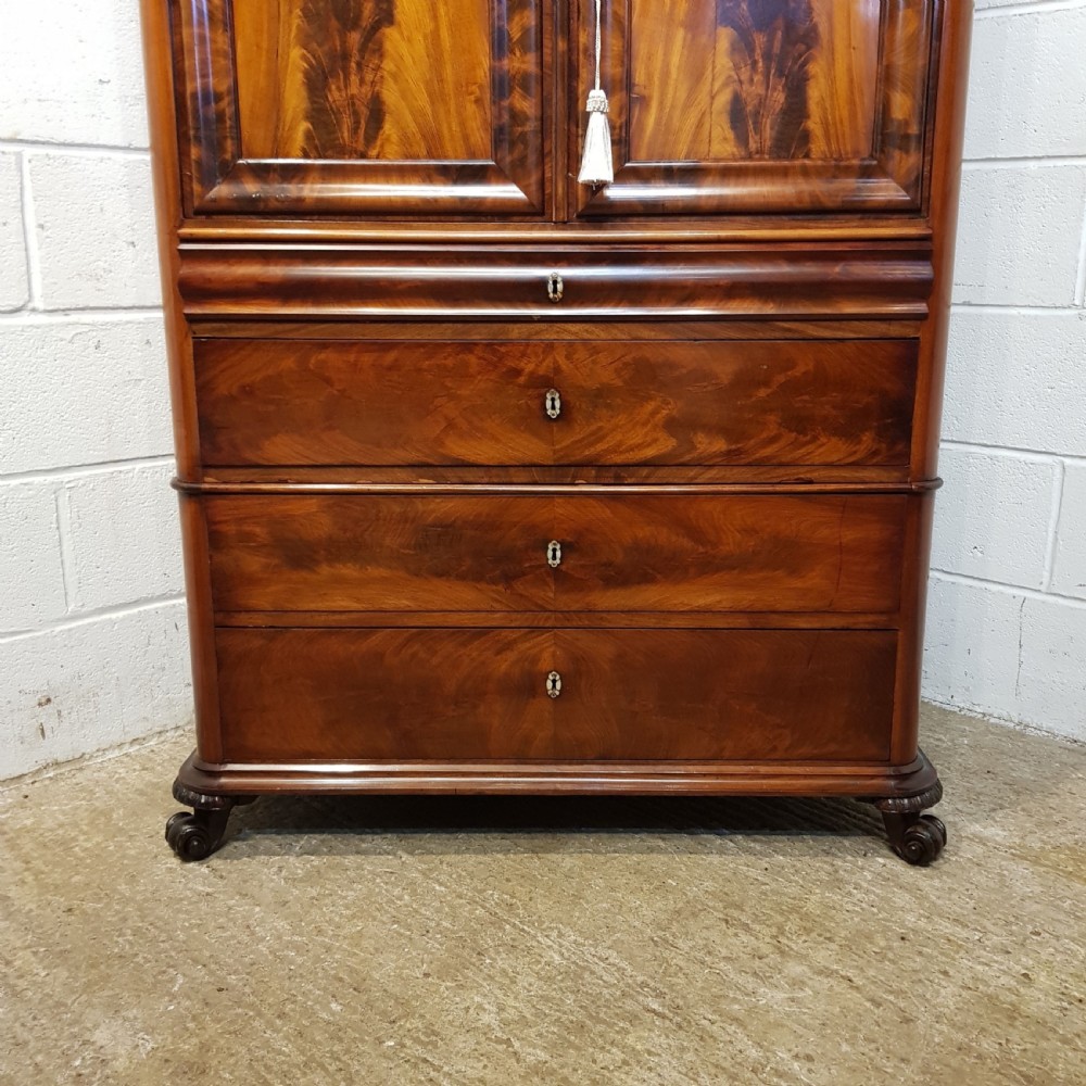 A nineteenth-century Biedermeier flame mahogany tall storage cabinet featuring double upper doors with figure-matched veneer and three full-width lower drawers. View XIII