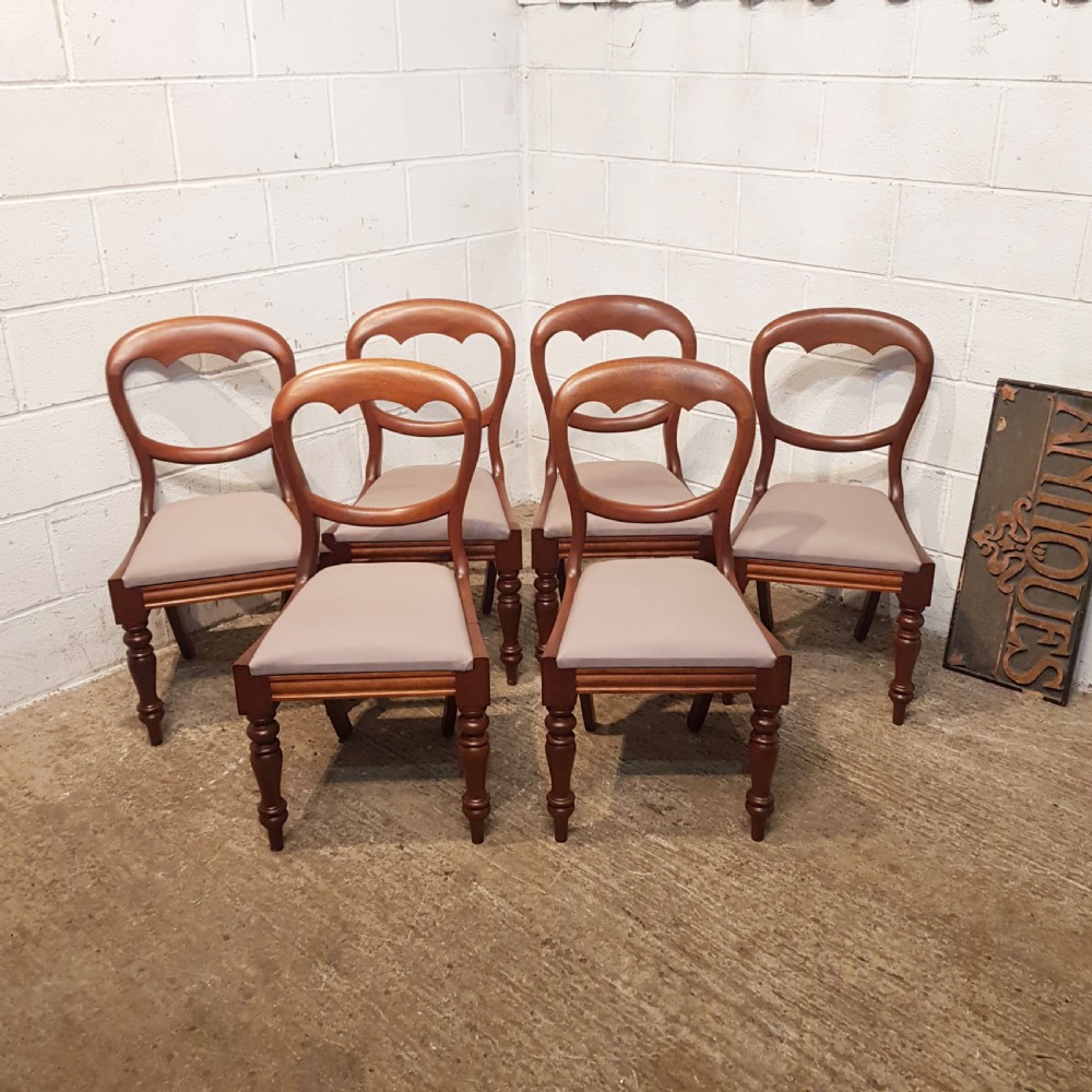 A set of six Victorian mahogany dining chairs featuring open balloon back frames, turned front legs, and neutral upholstered seats.