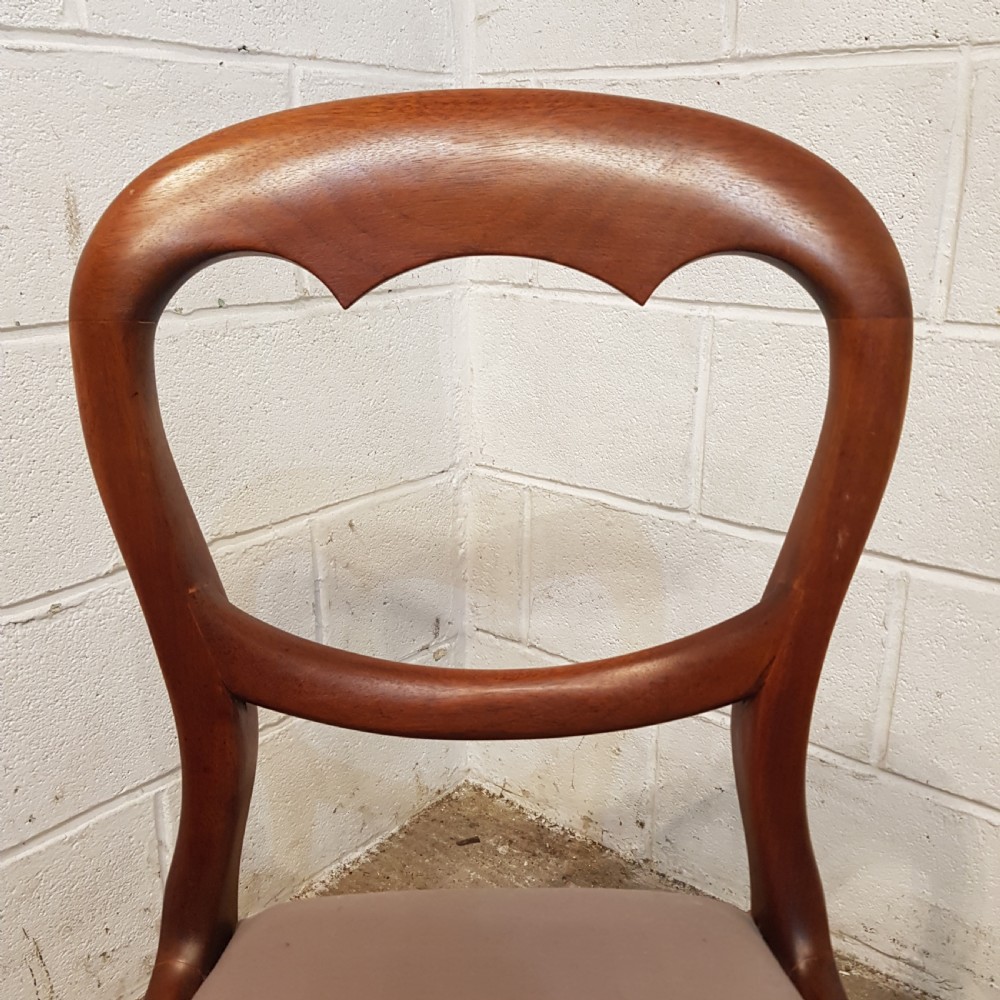 A set of six Victorian mahogany dining chairs featuring open balloon back frames, turned front legs, and neutral upholstered seats. View VI