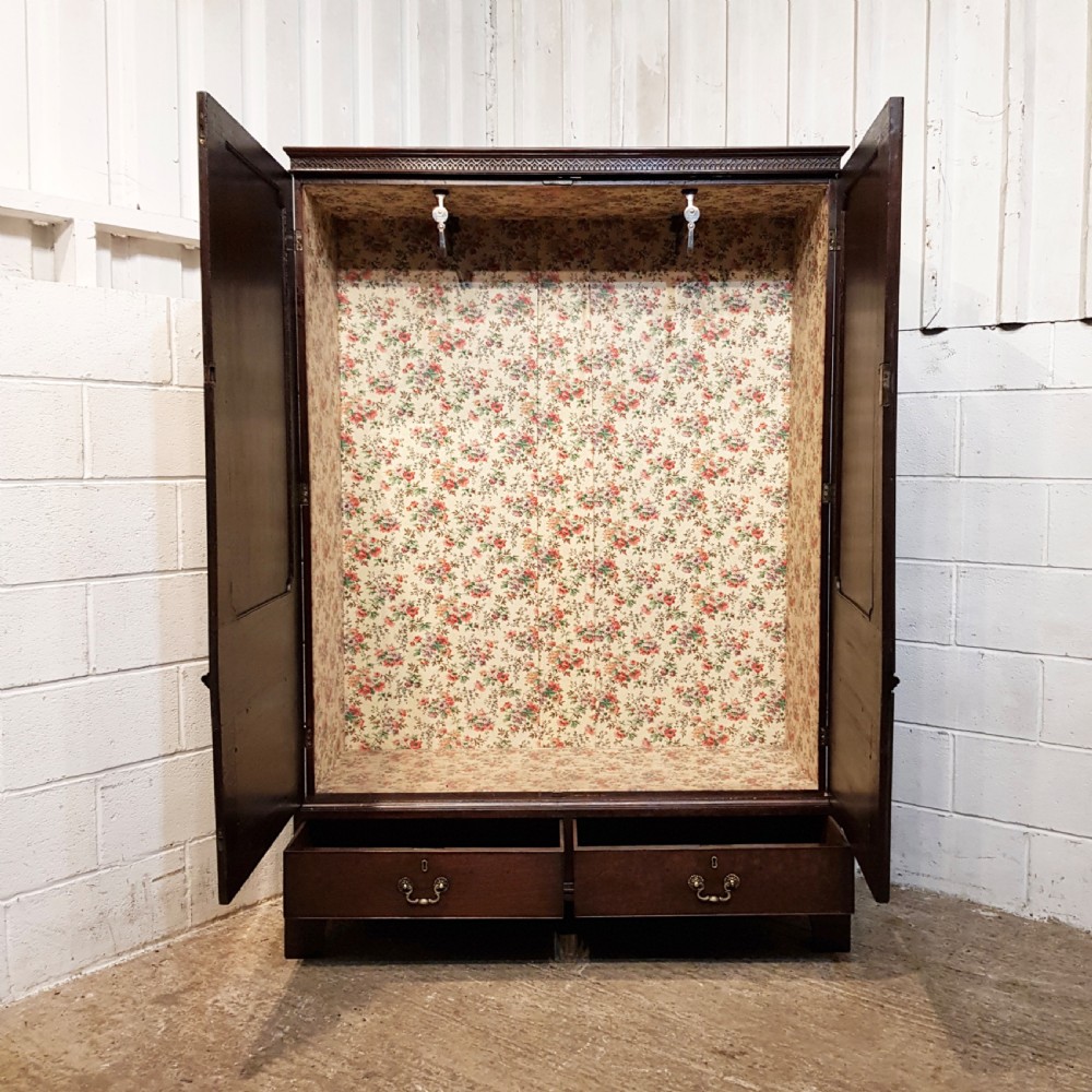 An eighteenth-century mahogany double wardrobe featuring flame mahogany panel doors decorated with carved corner rosettes and resting on bracket feet. View II
