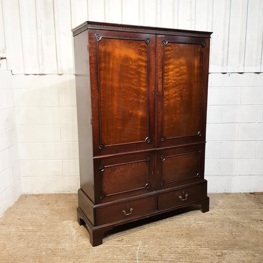 An eighteenth-century mahogany double wardrobe featuring flame mahogany panel doors decorated with carved corner rosettes and resting on bracket feet. View III