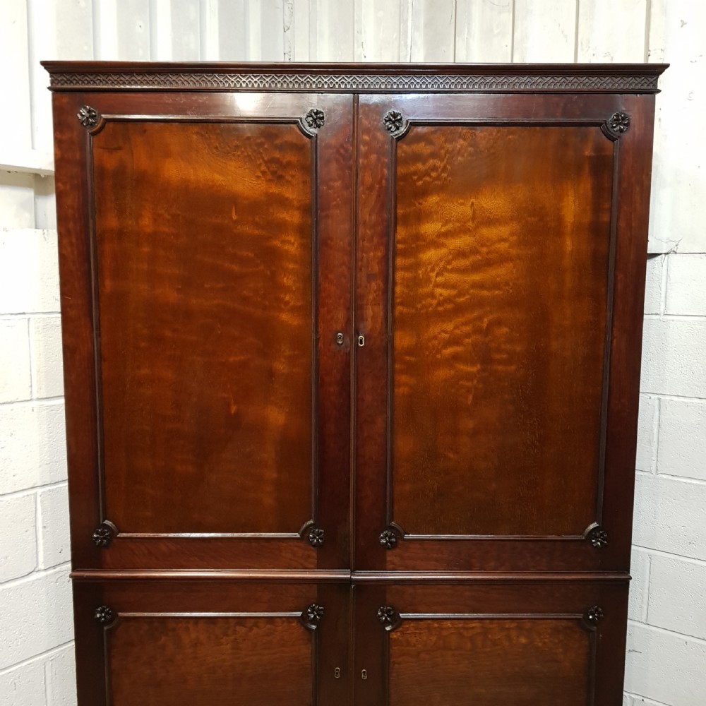 An eighteenth-century mahogany double wardrobe featuring flame mahogany panel doors decorated with carved corner rosettes and resting on bracket feet. View VIII