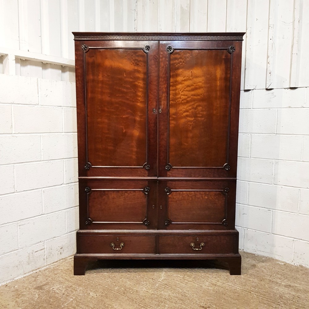 An eighteenth-century mahogany double wardrobe featuring flame mahogany panel doors decorated with carved corner rosettes and resting on bracket feet. View X