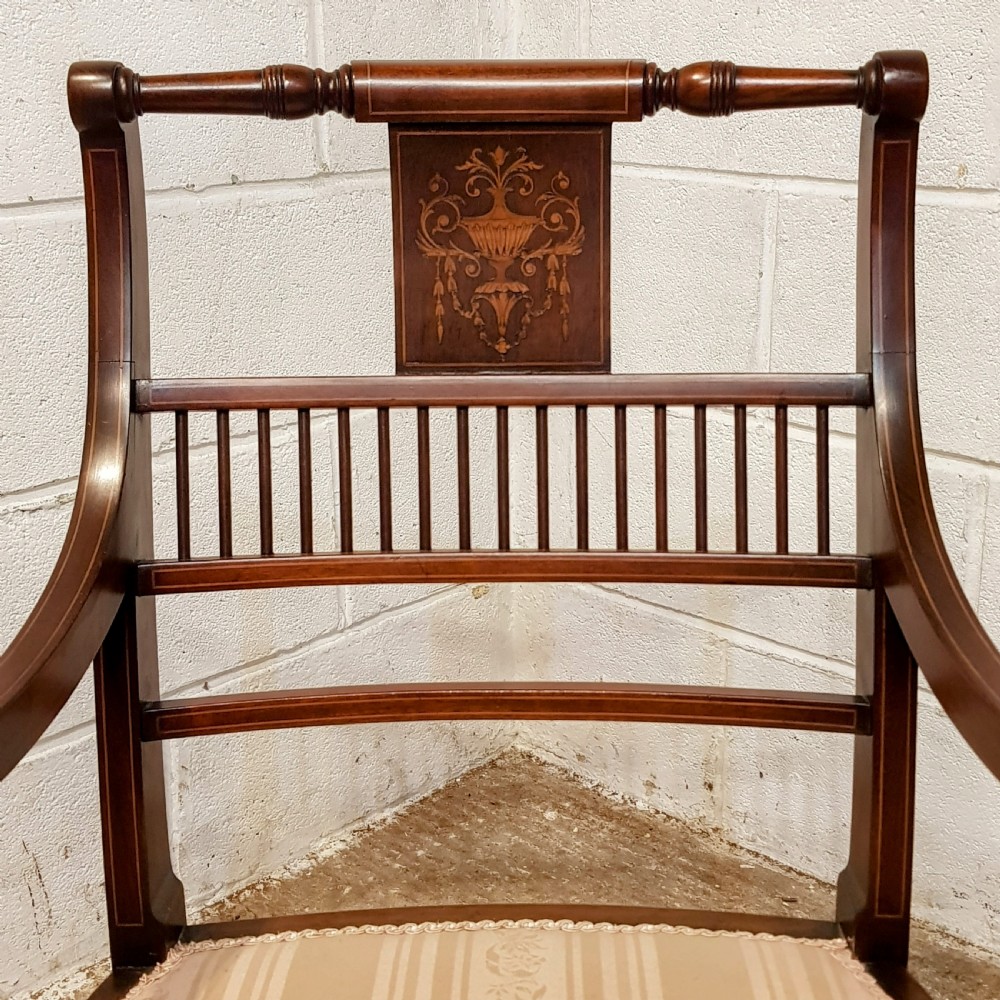 A pair of Edwardian mahogany armchairs featuring inlaid marquetry backsplats, vertical spindles, sweeping armrests, and striped fabric upholstery. View II