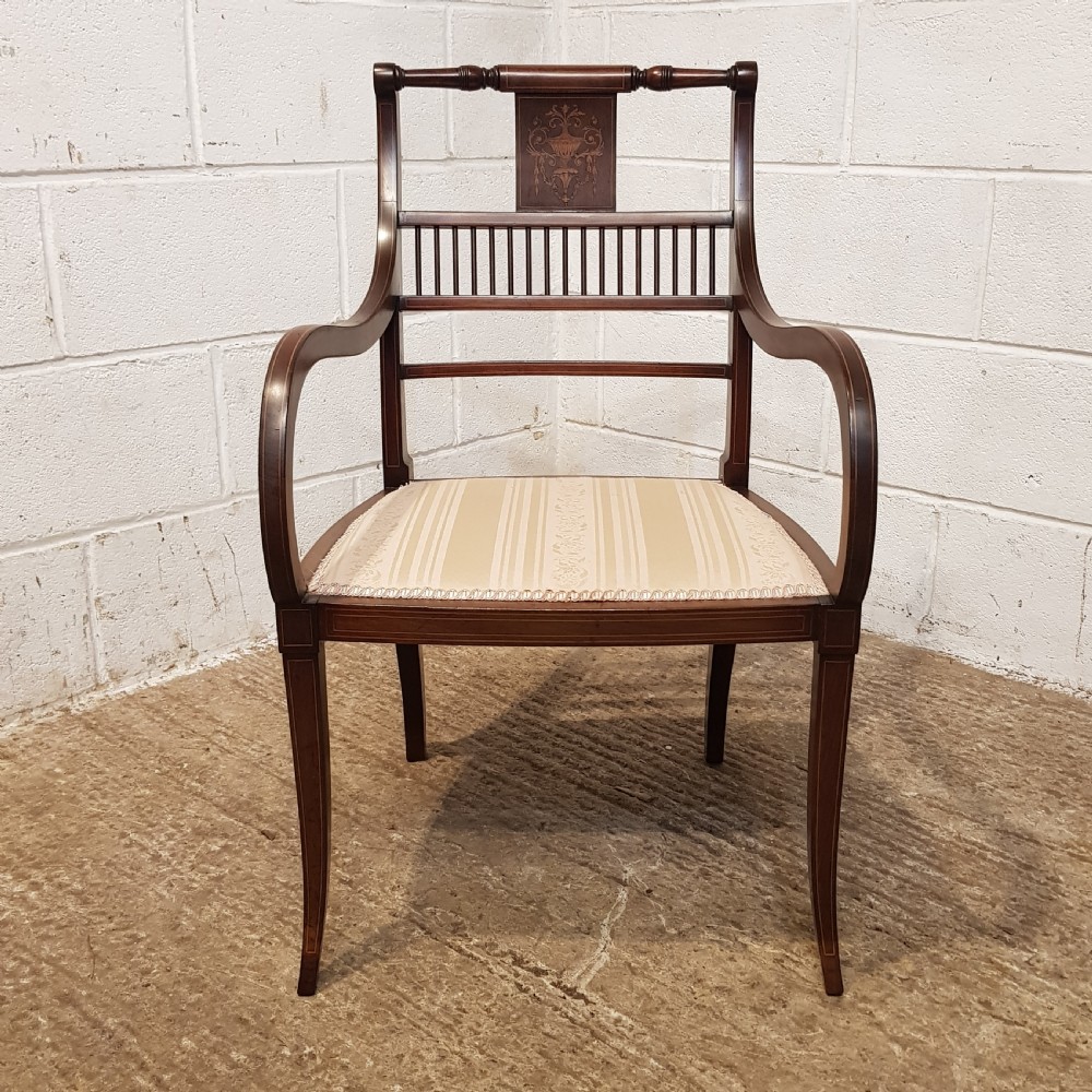 A pair of Edwardian mahogany armchairs featuring inlaid marquetry backsplats, vertical spindles, sweeping armrests, and striped fabric upholstery. View V