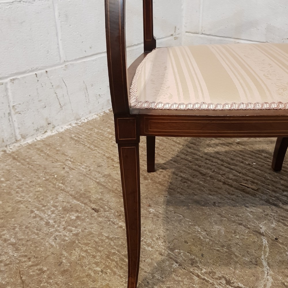 A pair of Edwardian mahogany armchairs featuring inlaid marquetry backsplats, vertical spindles, sweeping armrests, and striped fabric upholstery. View VII