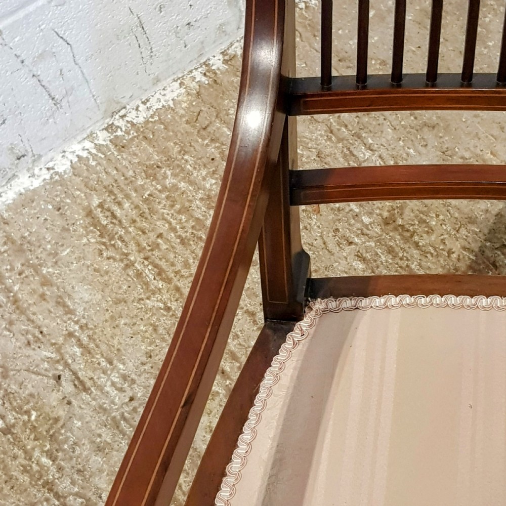 A pair of Edwardian mahogany armchairs featuring inlaid marquetry backsplats, vertical spindles, sweeping armrests, and striped fabric upholstery. View VIII