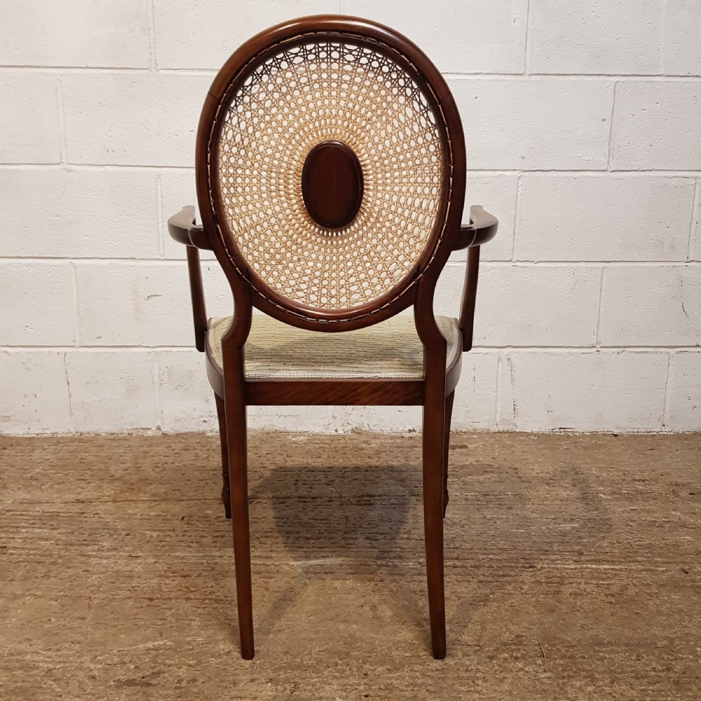 A mahogany armchair featuring an oval woven cane back with a central timber medallion, curved armrests, and turned front legs. View II