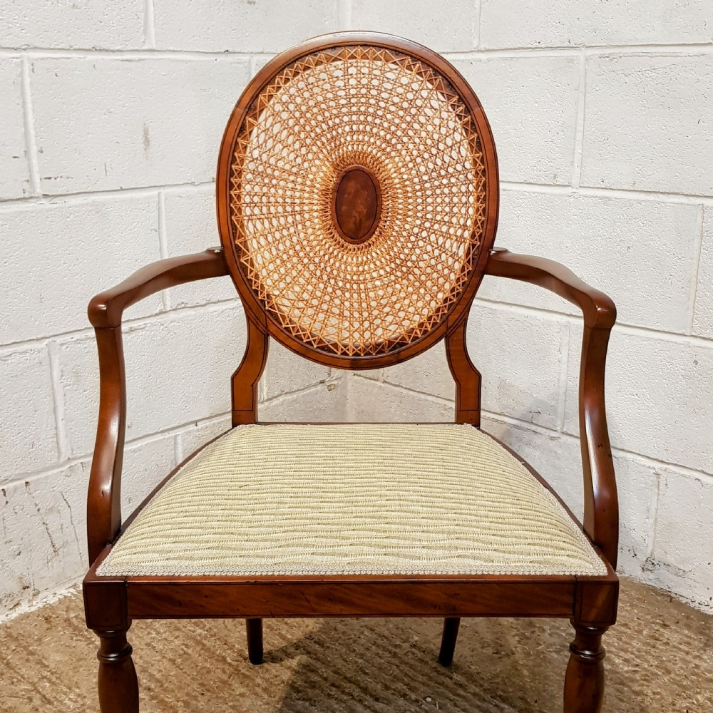 A mahogany armchair featuring an oval woven cane back with a central timber medallion, curved armrests, and turned front legs. View III