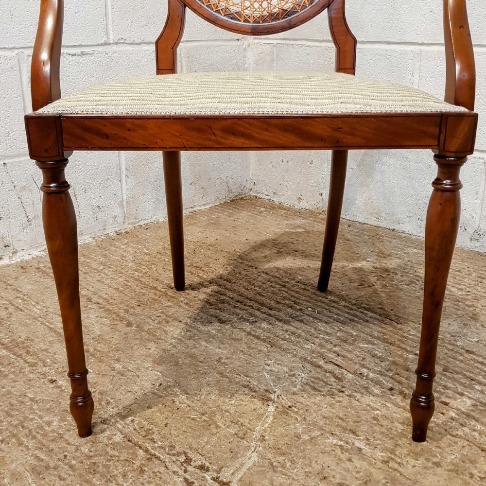 A mahogany armchair featuring an oval woven cane back with a central timber medallion, curved armrests, and turned front legs. View V