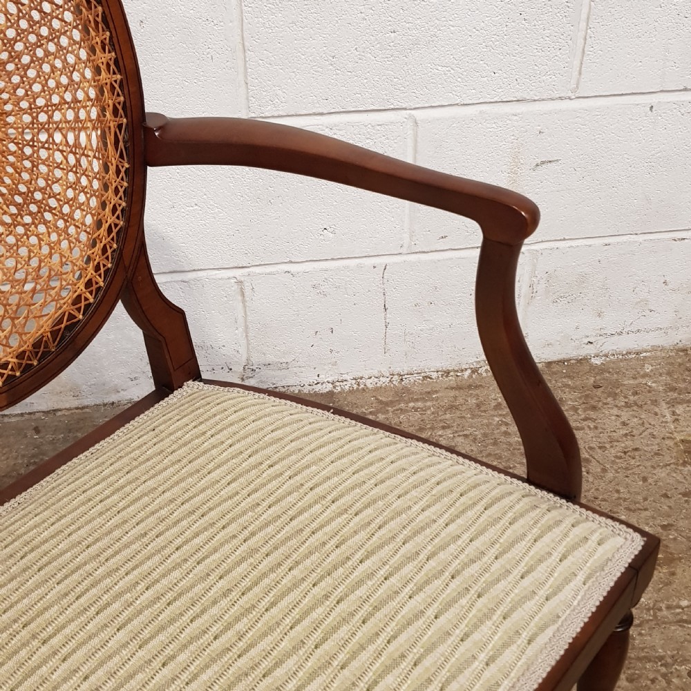 A mahogany armchair featuring an oval woven cane back with a central timber medallion, curved armrests, and turned front legs. View VII