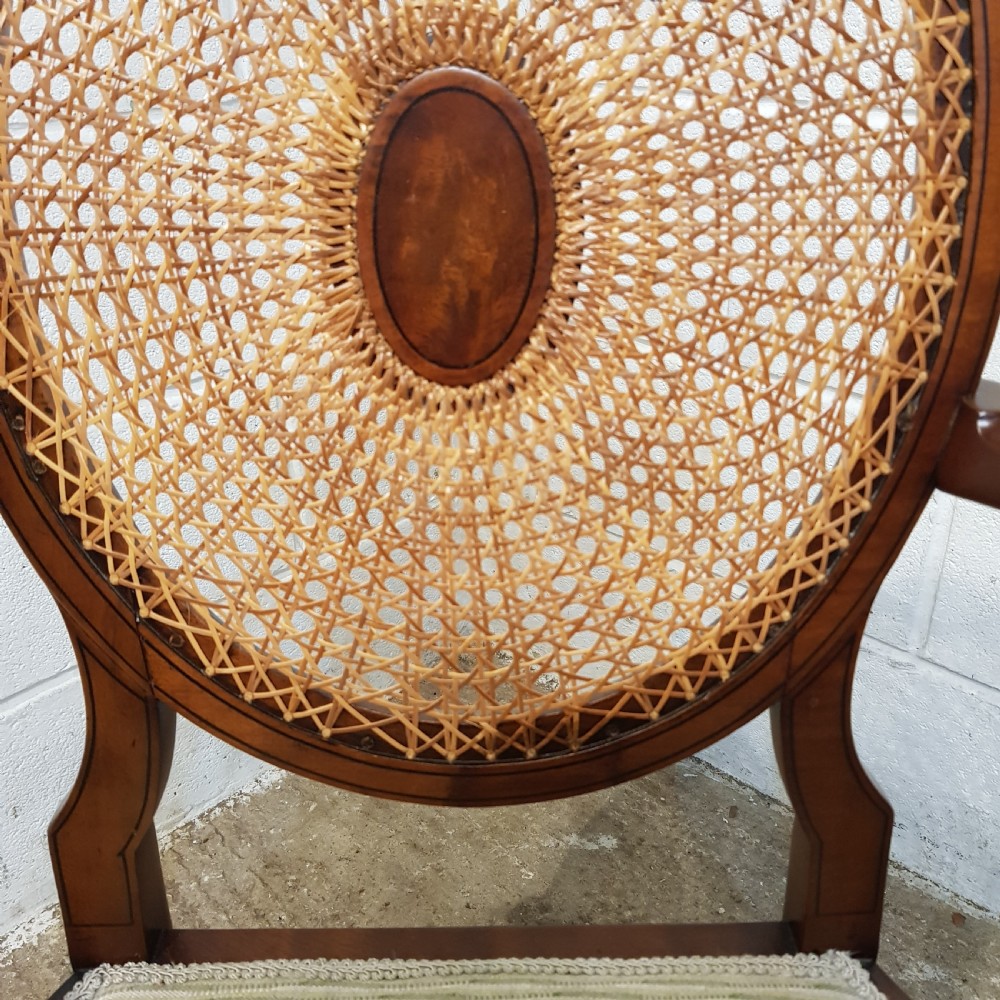 A mahogany armchair featuring an oval woven cane back with a central timber medallion, curved armrests, and turned front legs. View VIII