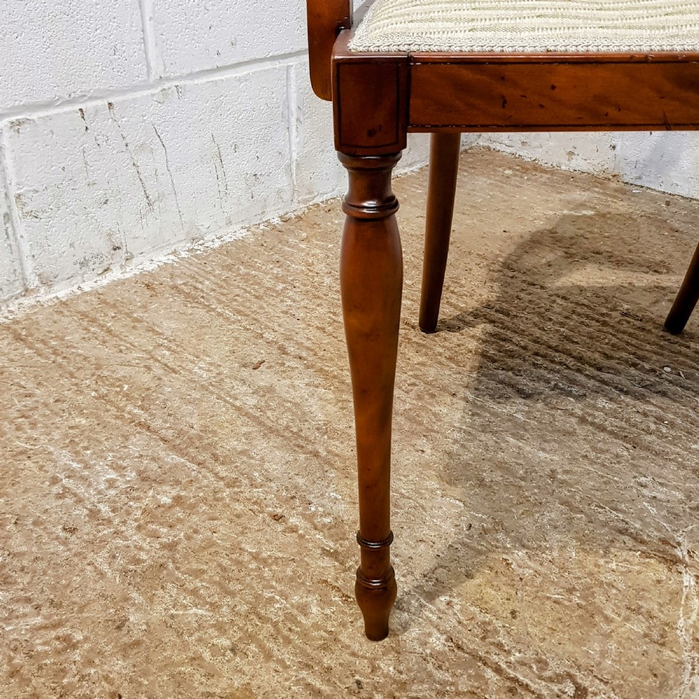 A mahogany armchair featuring an oval woven cane back with a central timber medallion, curved armrests, and turned front legs. View IX