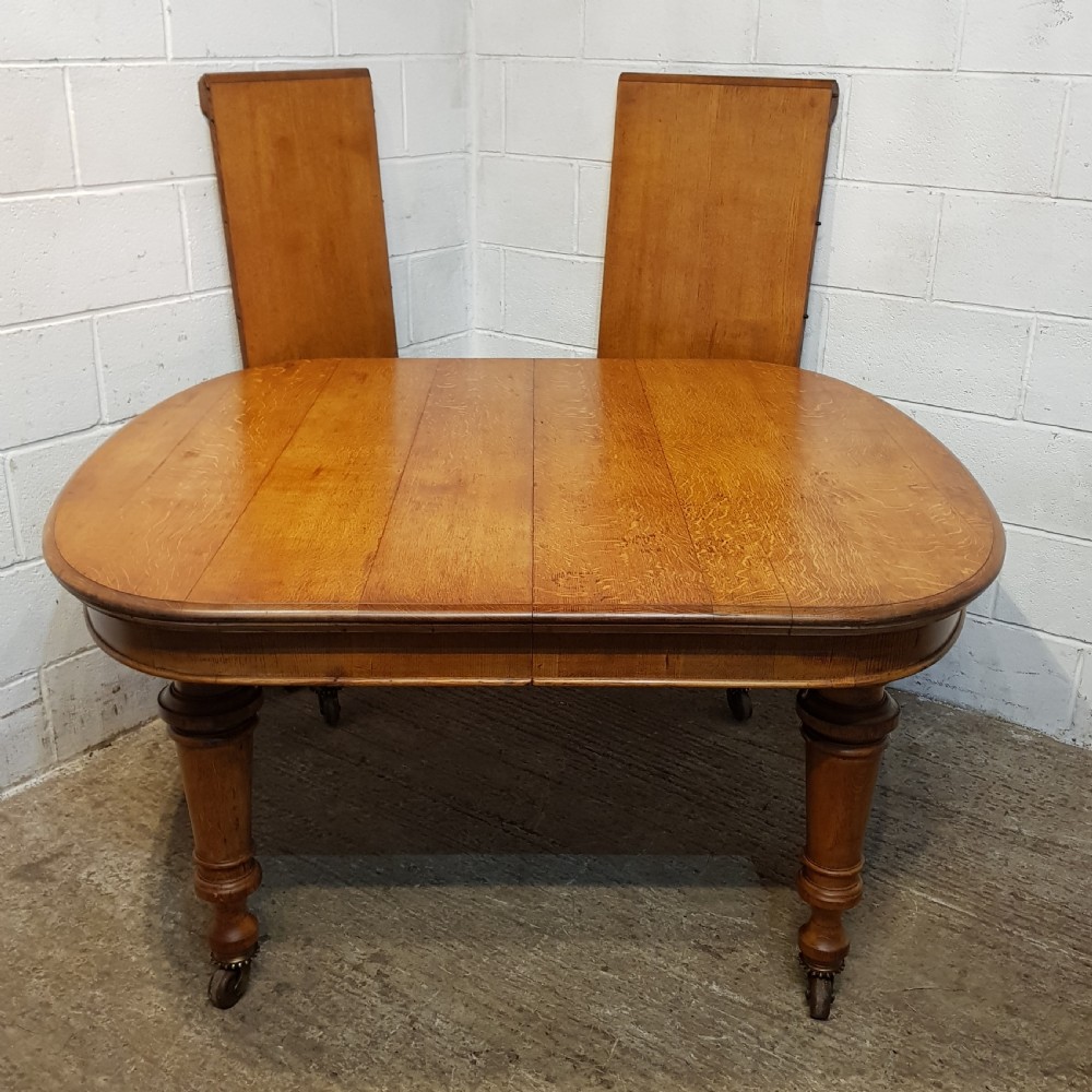 AN ANTIQUE VICTORIAN OAK EXTENDING WIND OUT DINING TABLE WITH TWO EXTRA LEAVES View II