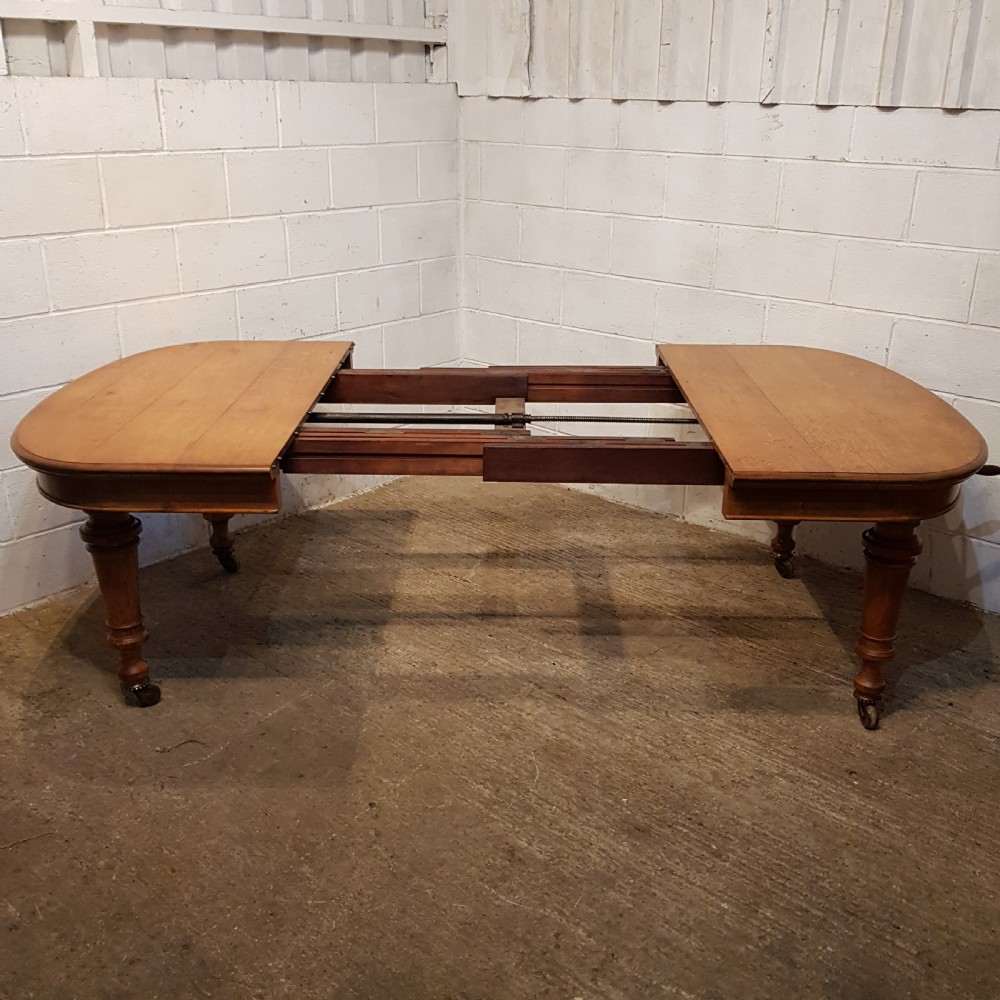 AN ANTIQUE VICTORIAN OAK EXTENDING WIND OUT DINING TABLE WITH TWO EXTRA LEAVES View IV