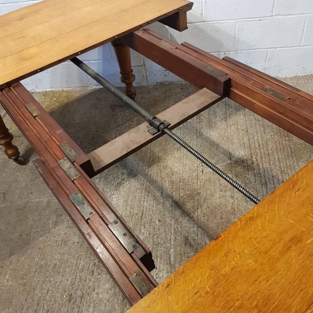 AN ANTIQUE VICTORIAN OAK EXTENDING WIND OUT DINING TABLE WITH TWO EXTRA LEAVES View VI