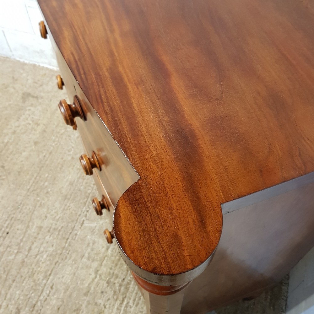 An antique Victorian bow-fronted Scotch chest of drawers featuring flame mahogany veneer, turned side columns, and turned wooden knobs. View VI