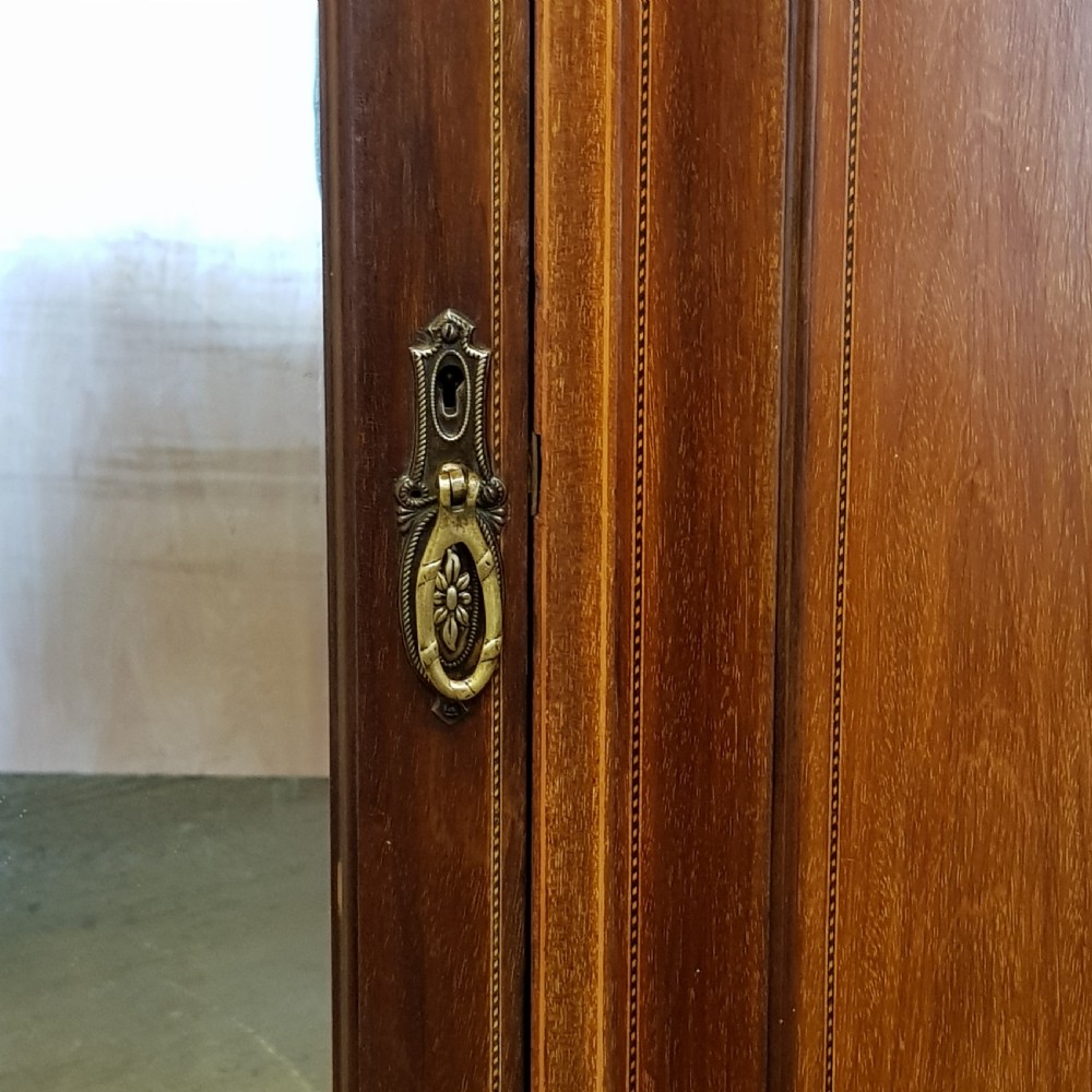 An Edwardian mahogany wardrobe with two outer mirrored doors, a central panel featuring wood inlay, and two drawers at the base. View II