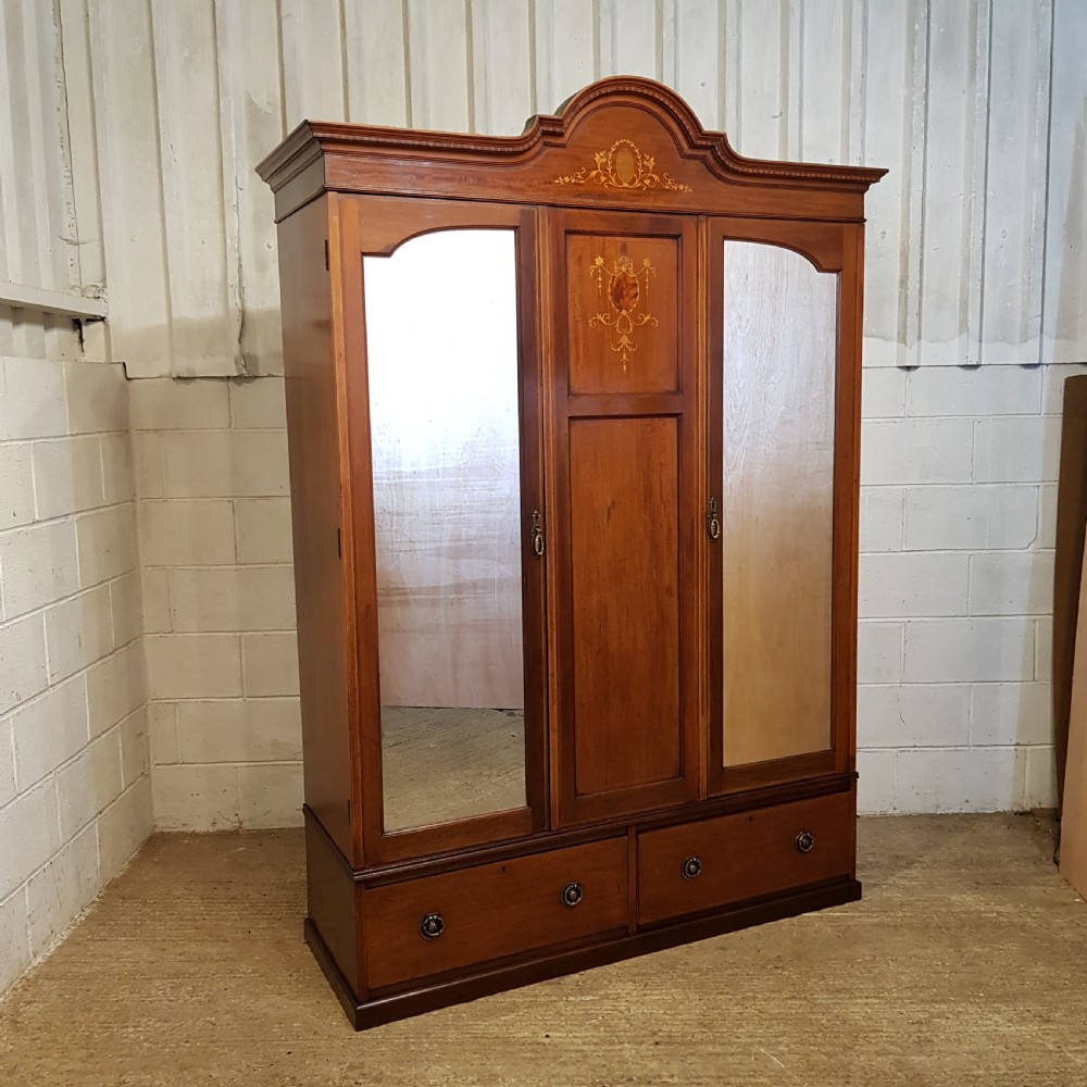 An Edwardian mahogany wardrobe with two outer mirrored doors, a central panel featuring wood inlay, and two drawers at the base. View VI