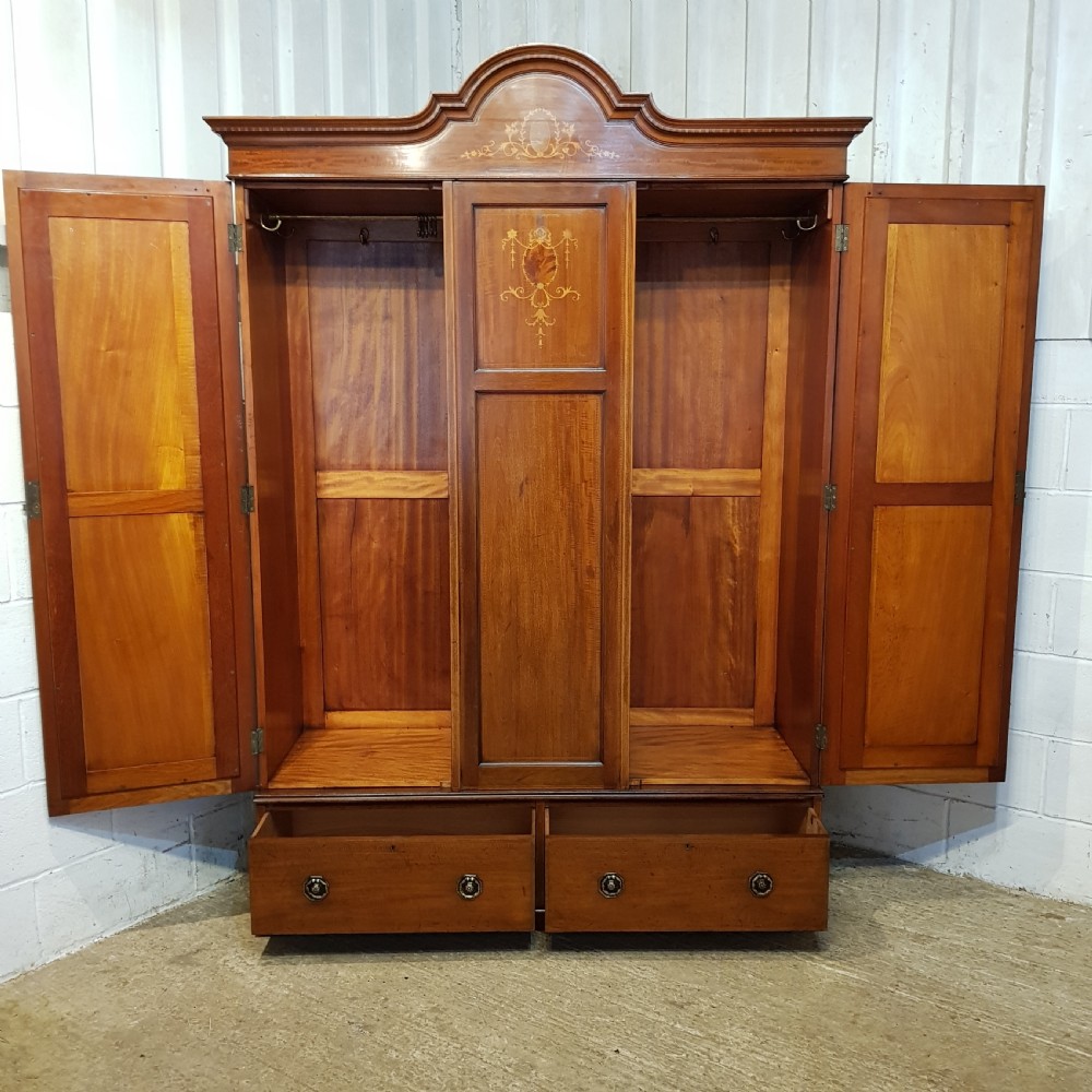 An Edwardian mahogany wardrobe with two outer mirrored doors, a central panel featuring wood inlay, and two drawers at the base. View VII
