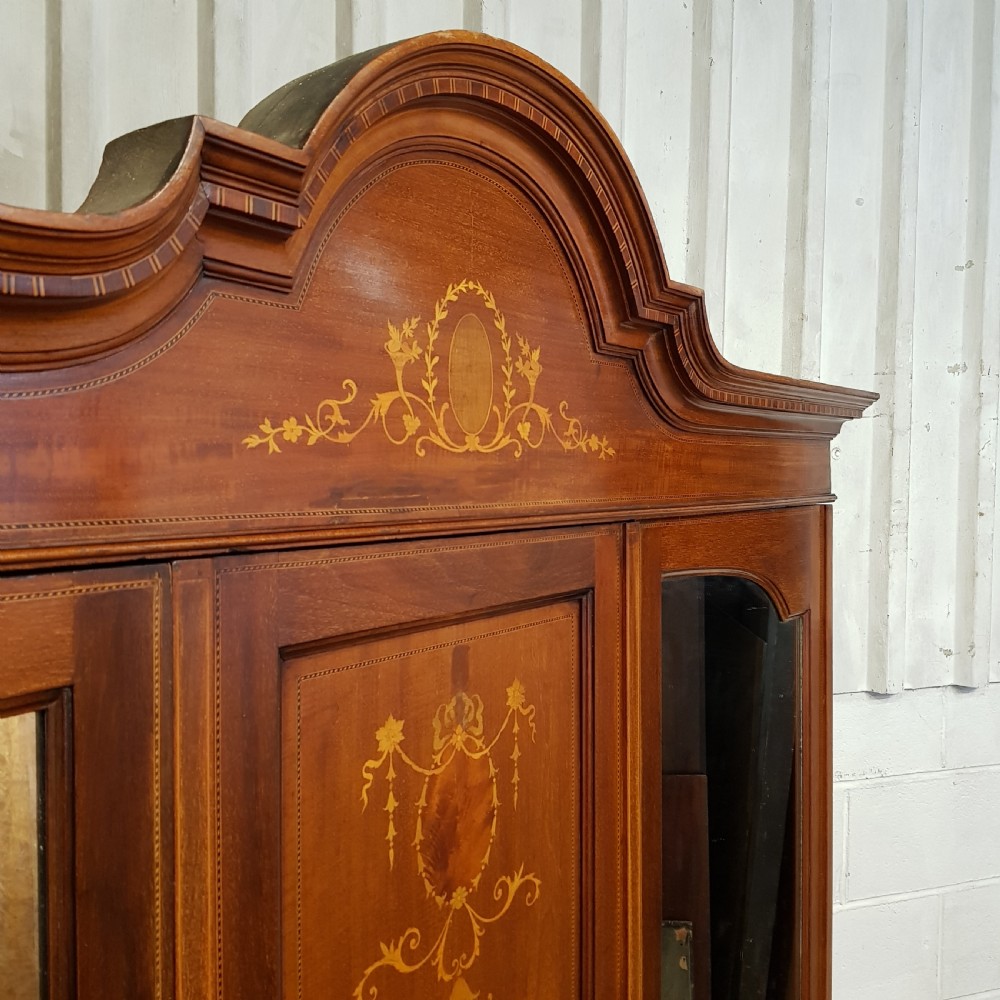 An Edwardian mahogany wardrobe with two outer mirrored doors, a central panel featuring wood inlay, and two drawers at the base. View VIII
