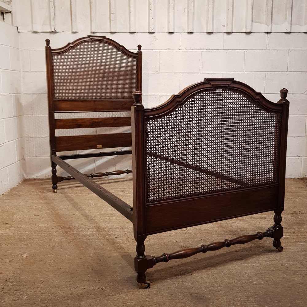 BY HEALS OF LONDON AN ANTIQUE PAIR OF WALNUT FRAMED SINGLE BEDS WITH BERGERE PANELS C1900