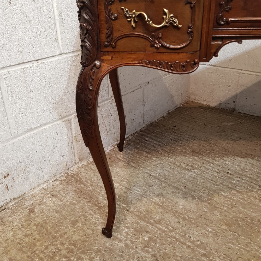 A late 19th-century French mahogany writing desk with a serpentine front, red leather inset top, three carved drawers, and slender cabriole legs. View III