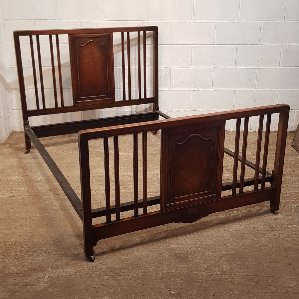 An antique dark walnut double bedstead featuring a central arched panel flanked by vertical slats on both the headboard and footboard, set with metal side rails. View VII