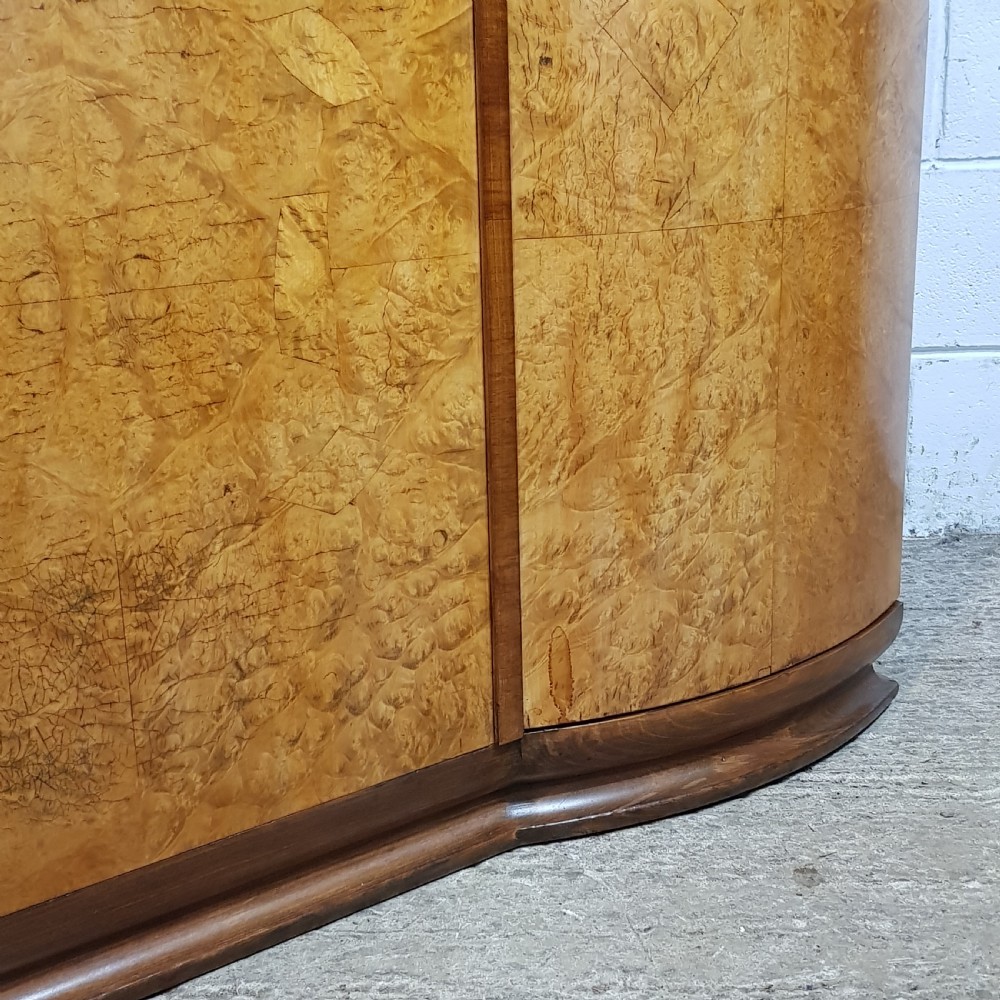 An Art Deco triple wardrobe crafted from highly figured burr walnut featuring curved outer doors and vertical metal handles. View II
