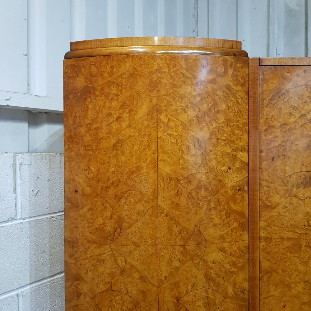 An Art Deco triple wardrobe crafted from highly figured burr walnut featuring curved outer doors and vertical metal handles. View V