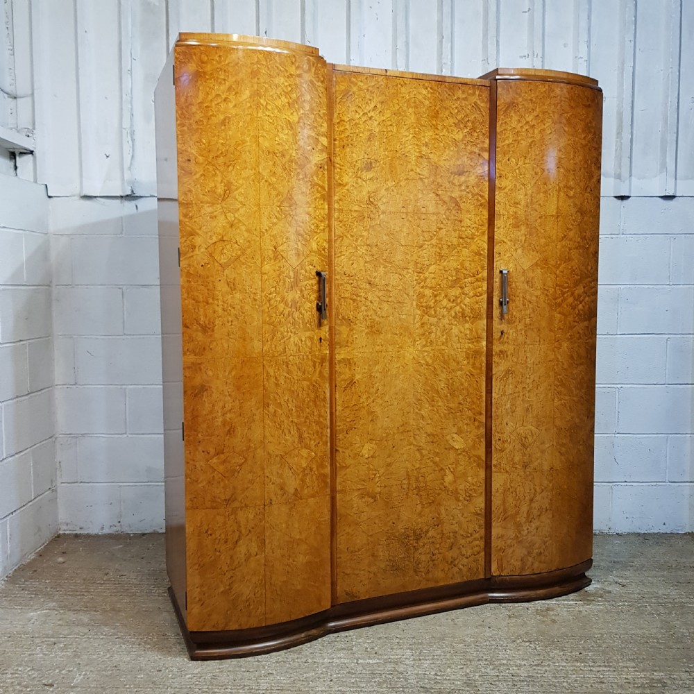 An Art Deco triple wardrobe crafted from highly figured burr walnut featuring curved outer doors and vertical metal handles. View VII