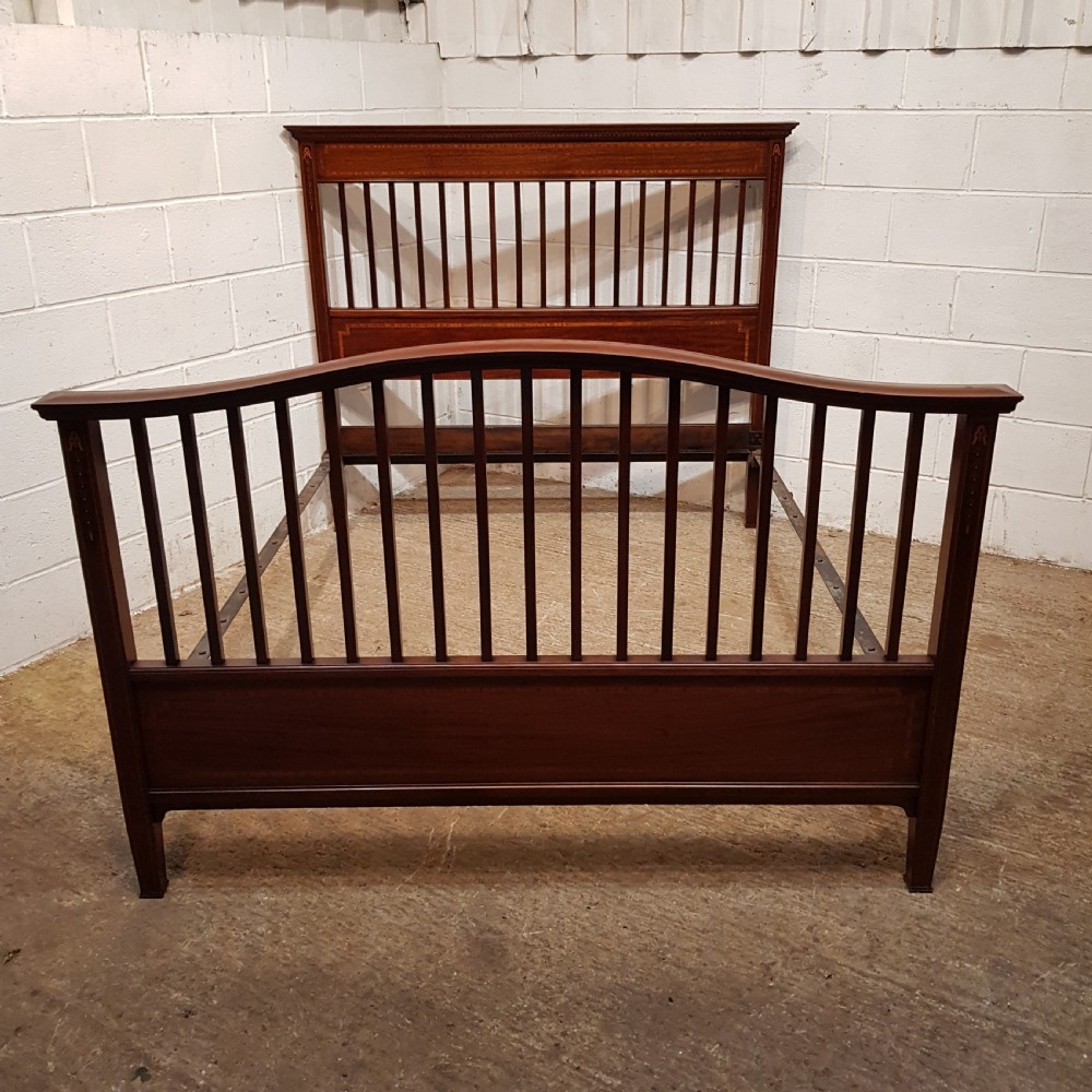 An Edwardian mahogany king size bedstead featuring vertical slatted panels on both headboard and footboard, decorated with fine wood inlay.