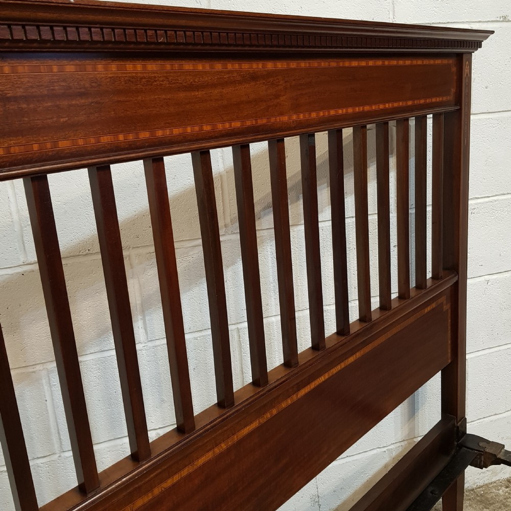 An Edwardian mahogany king size bedstead featuring vertical slatted panels on both headboard and footboard, decorated with fine wood inlay. View VI
