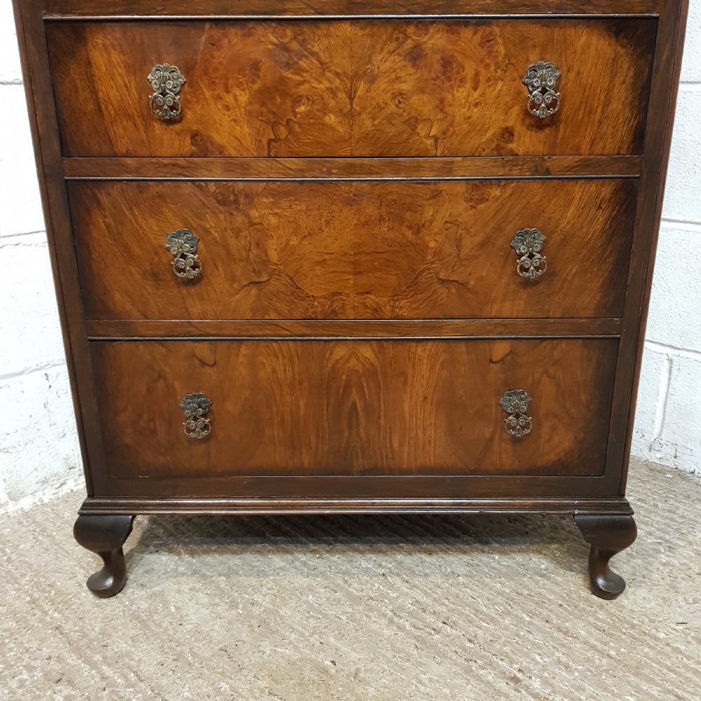 A 1920s burr walnut tallboy featuring an arched top two-door cabinet over three wide drawers with ornamental brass handles and cabriole feet. View II