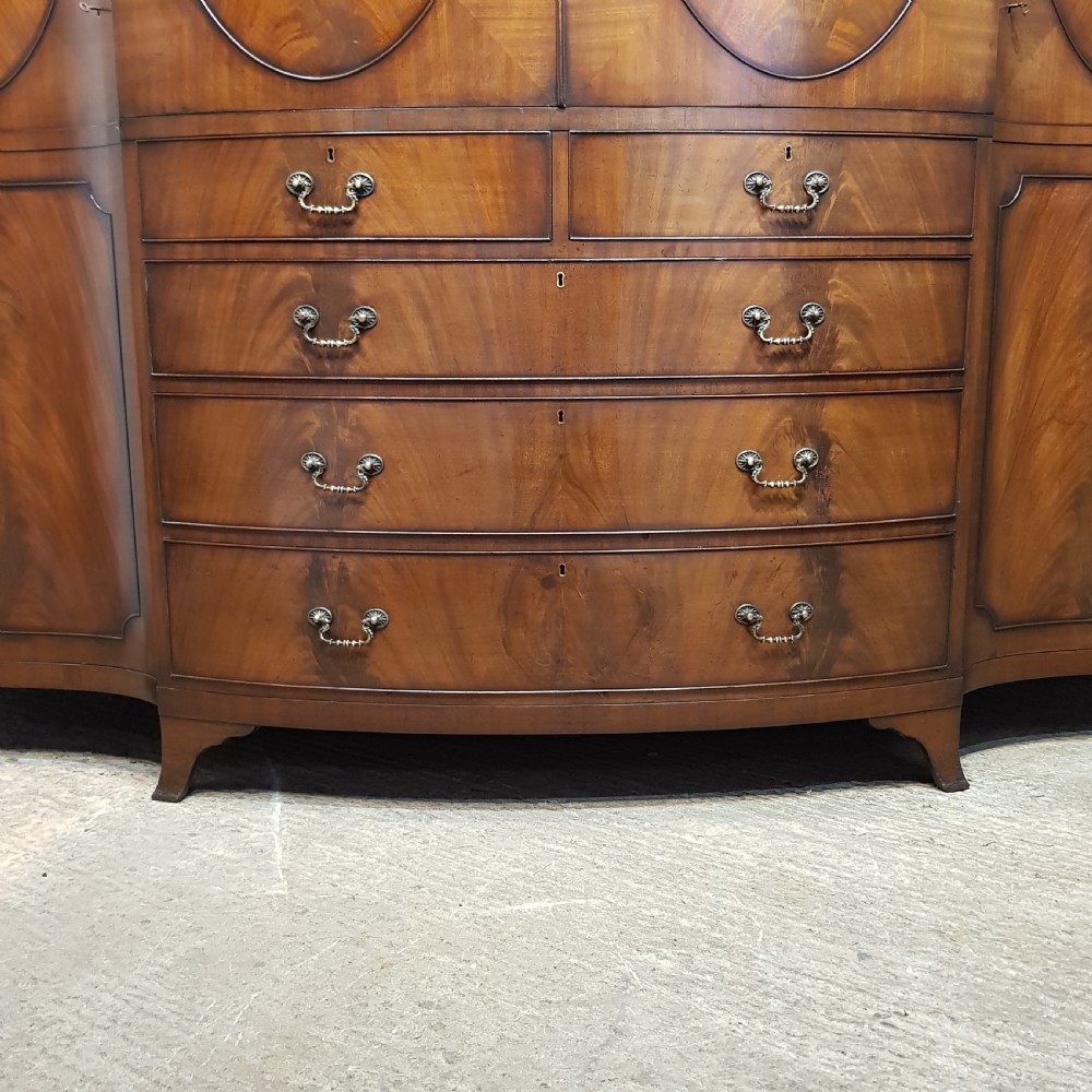 A large mahogany breakfront triple wardrobe featuring oval flame mahogany veneer panels on the doors and a central chest of drawers. View II