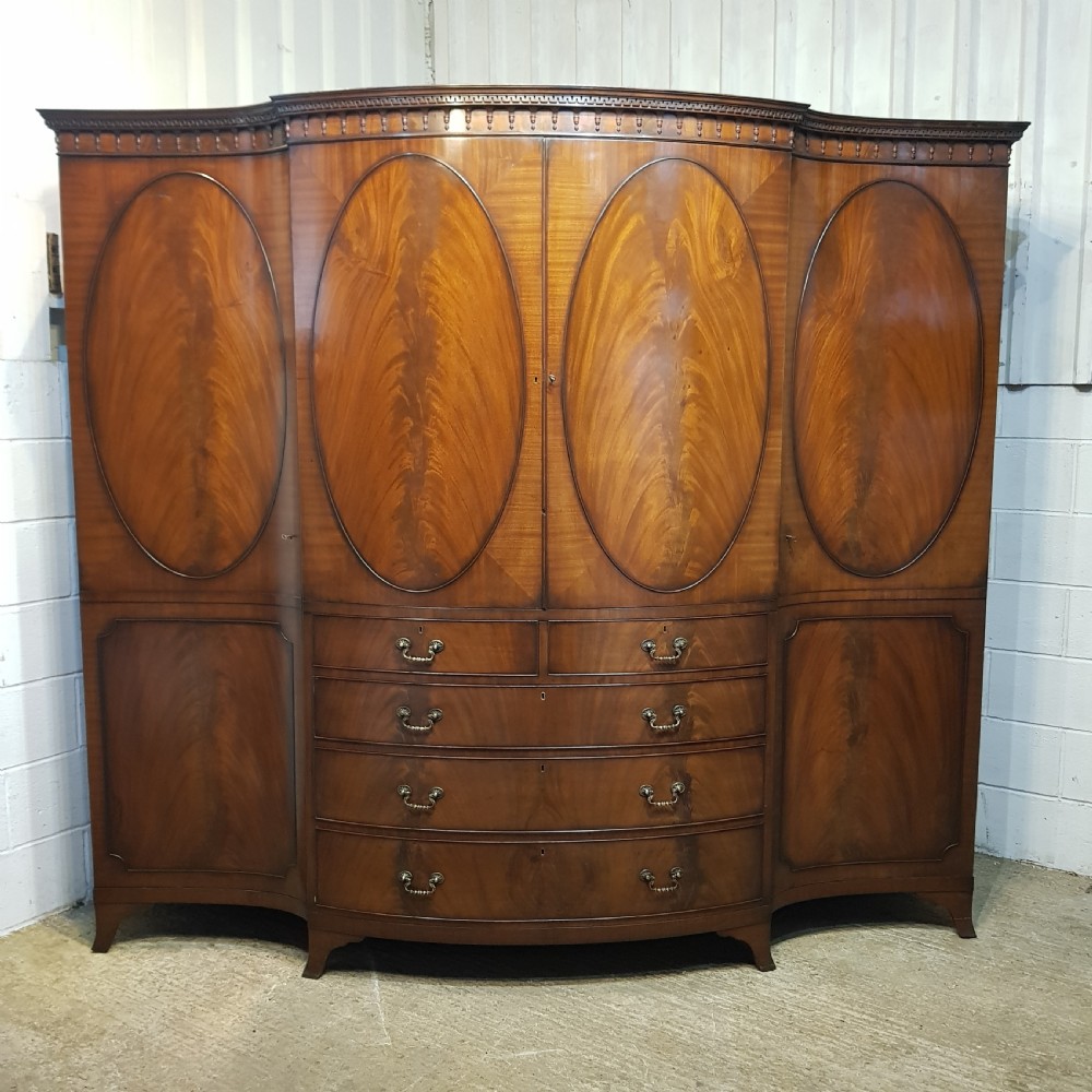 A large mahogany breakfront triple wardrobe featuring oval flame mahogany veneer panels on the doors and a central chest of drawers. View III