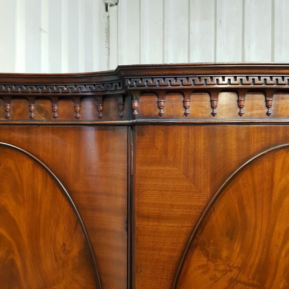 A large mahogany breakfront triple wardrobe featuring oval flame mahogany veneer panels on the doors and a central chest of drawers. View VI