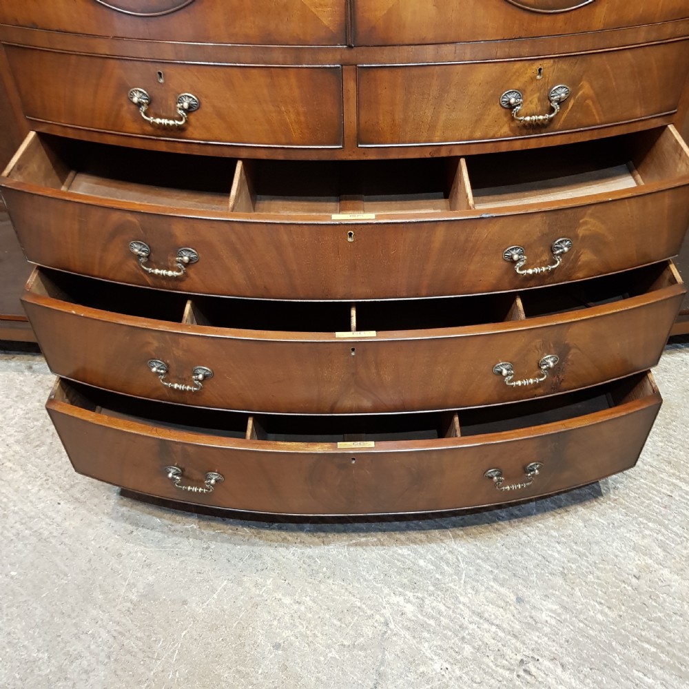 A large mahogany breakfront triple wardrobe featuring oval flame mahogany veneer panels on the doors and a central chest of drawers. View VII