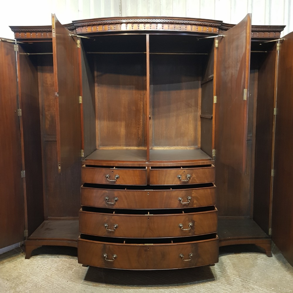 A large mahogany breakfront triple wardrobe featuring oval flame mahogany veneer panels on the doors and a central chest of drawers. View XII